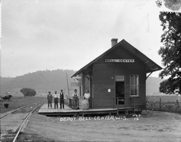 Exterior view of the Bell Center depot with five men posing on the platform.