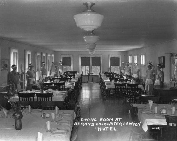 View down middle of the dining room at Berry's Coldwater Canyon Resort. Female servers stand along the walls near the tables.