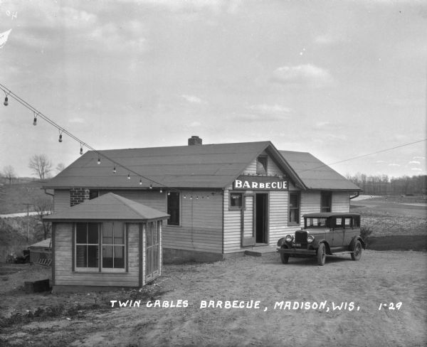 Twin Gables Barbecue Exterior of the Twin Gable Barbecue restaurant, where a car is parked at the entrance.