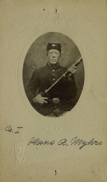 Waist-up seated oval studio portrait of Hans A. Myhre, a private in Company I, 15th Wisconsin Infantry in uniform holding a musket across his chest. The following information was obtained from the Regimental and Descriptive Rolls, Volume 20: He held residence in St. Laurence, Wisconsin. On December 9, 1861, he enlisted in Scandinavia, Wisconsin and on December 20, 1861, he was mustered into service in Madison, Wisconsin at the age of 21. He was mustered out of service with company on February 10, 1865, at Chattanooga, Tennessee.