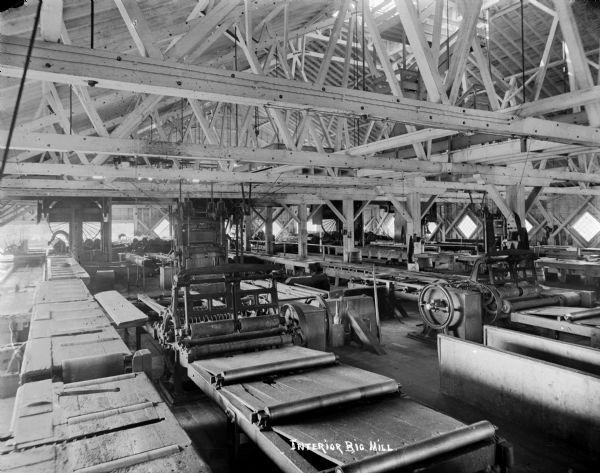 Interior view of large room filled with machinery inside a lumber mill.