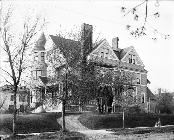 View from street of exterior of the Leslie Wilson residence, a large Victorian house, at 320 Superior Street. A sidewalk runs in front of the house and trees stand in between the sidewalk and the street. Wilson was proprietor of Wilson Wholesale Grocery.