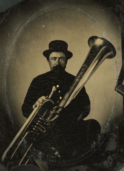 Tintype portrait of Charles C. Stone of Brodhead, Wisconsin, member of the 3rd Wisconsin Infantry band. He is seated in uniform and holds a tuba. The buttons on his uniform are hand-colored gold.
