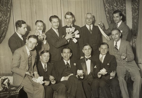 Ben Bergor, a Madison area magician (standing third from the left), with a group of Chicago area magicians. Identified individuals are (seated, left to right) Johnny Platt, Jimmy Thompson, William Dornfield, George Troseth, Axel Helstrom, and Bob Letz. The identified individuals in the back row on either side of Bergor are Joe Berg and Laurence Ireland. This photograph is undated, but it may be a 1937 gathering of Chicago Society Association of Magicians at which Bergor was voted an honorary member. Bergor, who was said to have the fastest hands in the business, is shown doing one of his famous card tricks.