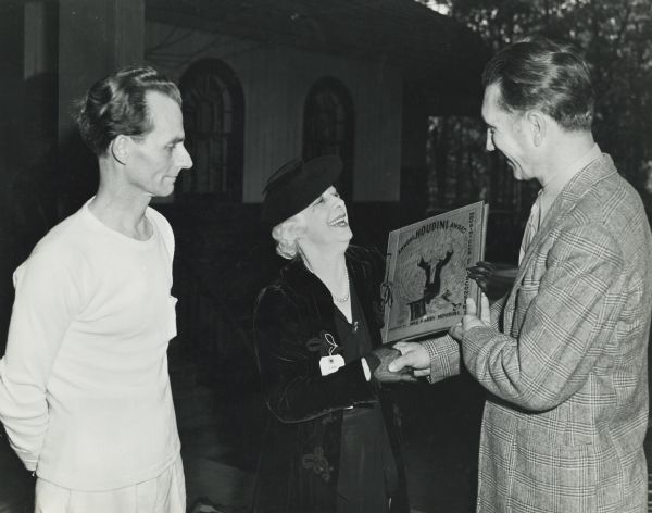 Mrs. Beatrice Houdini presenting the Houdini Award Album to Ben Bergor, a Madison magician. The award was made annually by the Houdini Club of Wisconsin to the best escape. Bergor won the award three years in a row and was granted permanent custody of the trophy. It is now part of his papers at the Wisconsin Historical Society. The other individual on the left has not been identified.