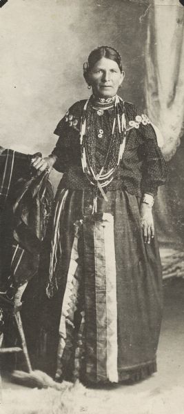 Full-length portrait in front of a painted backdrop of Mrs. Ketch ka mi, daughter of Potowatomi Indian Chief John Young.
