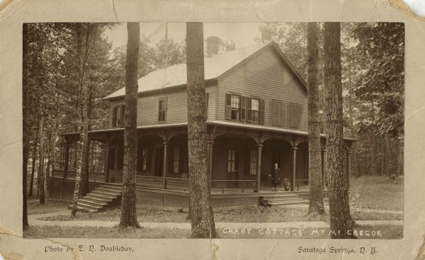 Exterior view of Grant Cottage with man and dog standing on the porch.