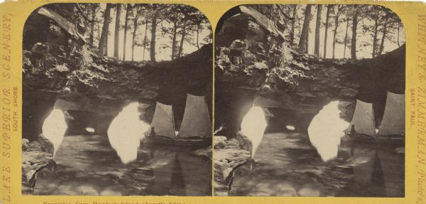 Stereograph of a sailboat in Excursion Cave, on Hemlock Island of the Apostle Islands. A man can be seen sitting in the boat.