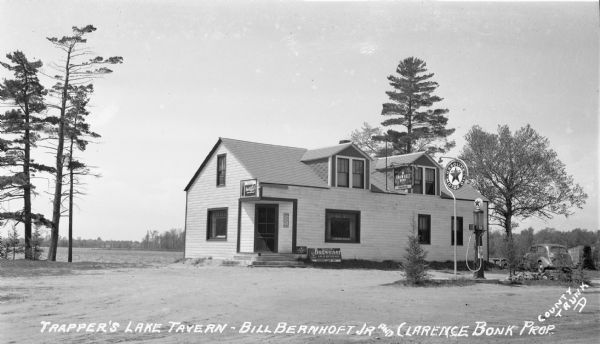 Trapper's Lake Tavern Gas pump and automobile next to a tavern on county Road D near Clam Lake.