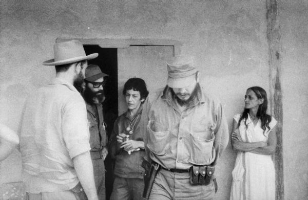 Meeting of members of the 26th of July Movement in front of a building in Oriente Province during the Cuban Revolution. Fidel Castro is in the foreground and Celia Sánchez is in front of the door.