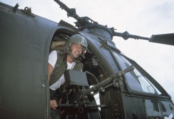 Portrait of a helicopter gunner at his gun in an H-21 Army helicopter in the mountain region of Vietnam.