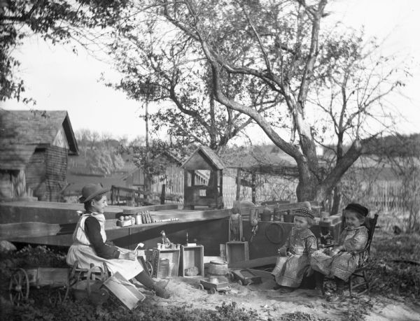 Jennie and Edgar Krueger (twins on right) and Effie Goetsch (Carr) playing with toys outdoors. Effie was the daughter of Ernest Samuel Goetsch and Anna Schumacher.