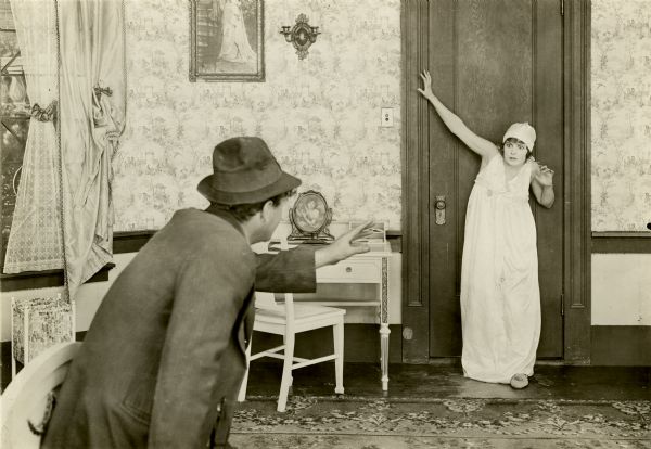 The robber Jimmy Briggs (played by Eugene Pallette) menaces Grace Remington (Norma Talmadege) in her bedroom in this scene still from the silent feature film "Going Straight."