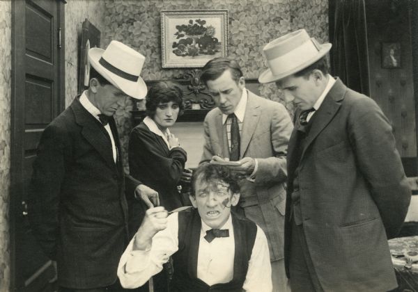 Mr. Pepper's butler (played by Philip Gastrock) describes how his master was murdered to a group including Jane Pepper (Irene Hunt), her brother (Jack Conway, in the light-colored suit), and the newspaperman (William Lowrey, wearing a hat with a broad band).