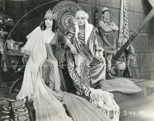 Betty Blythe as the Queen of Sheba and Fritz Leiber as King Solomon in a still from "The Queen of Sheba," a silent William Fox mega-production of 1921. They are seated on thrones with guards standing nearby.
