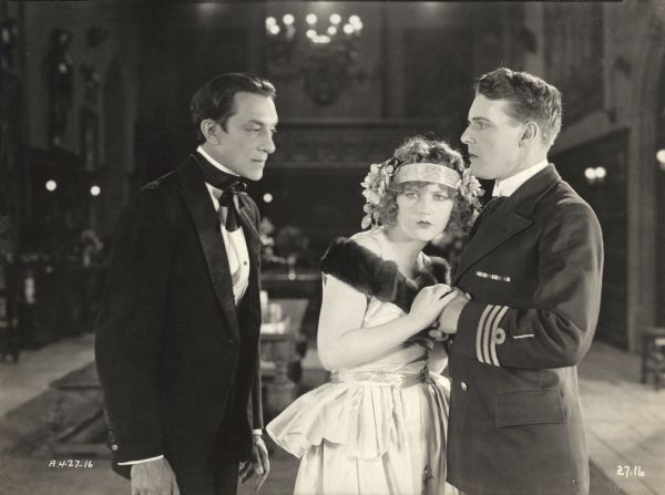 Dr. Dimitrius (played by Pedro de Cordoba) looks meaningfully at Diana May (Marion Davies) who clings to Commander Richard Cleeve (Forrest Stanley) in a scene still from "The Young Diana."