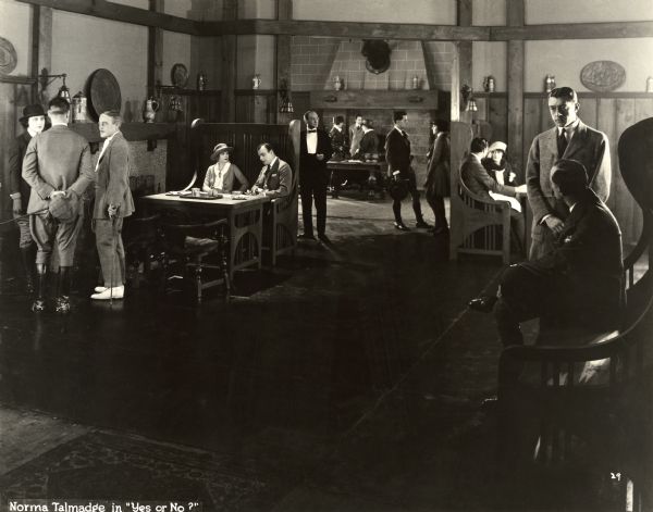 Margaret Vane (played by Norma Talmadge) has coffee with Paul Derreck (Lowell Sherman) in an exclusive hunting club in a scene still from "Yes or No" (1920). Scattered throughout the room are men and women dressed in equestrian costume: jodhpurs, clubbing coats, riding boots, and so on.