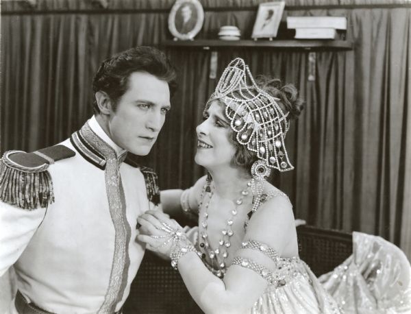 Prince Michael Orbeliana (played by Lou Tellegen in an aristocratic white military uniform) visits the opera singer Marcia Warren (Geraldine Farrar wearing a pearl-covered headdress) in her dressing room in this scene still from "The World and Its Woman."