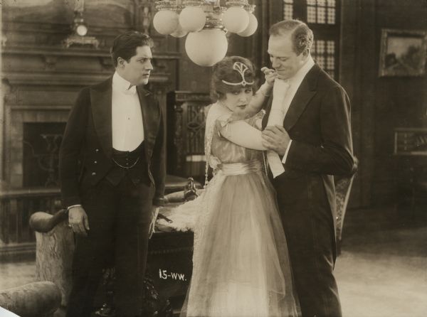 Marion Livingston (played by Ethel Clayton) adjusts the tie of Oliver Whitney (Montagu Love) as Howard Stanton (Carlyle Blackwell) looks on in a scene still from the 1916 silent film "A Woman's Way."