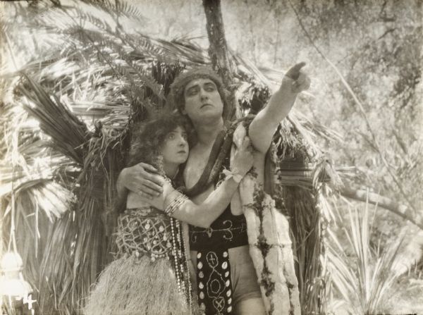 Enid Markey, in a grass skirt, plays Kalaniweo, the Polynesian chief's daughter. Embracing her is Willard Mack playing David Harmon, a shipwrecked lawyer in a scene still from "Aloha Oe."