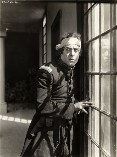 Robert Z. Leonard costumed as a first lieutenant in the U.S. Army in the Civil War, pauses warily by a window in a scene still for the silent drama "Betty's Dream Hero."
