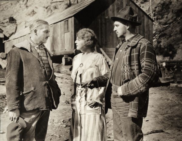 Lumberman Jack Fyfe (played by Wallace Reid in corduroy at left) is interested in Stella Benton (Kathlyn Williams). She is the cook for her brother Charlie Benton (Alfred Paget, right) at his lumber camp in this scene still for the silent drama "Big Timber."