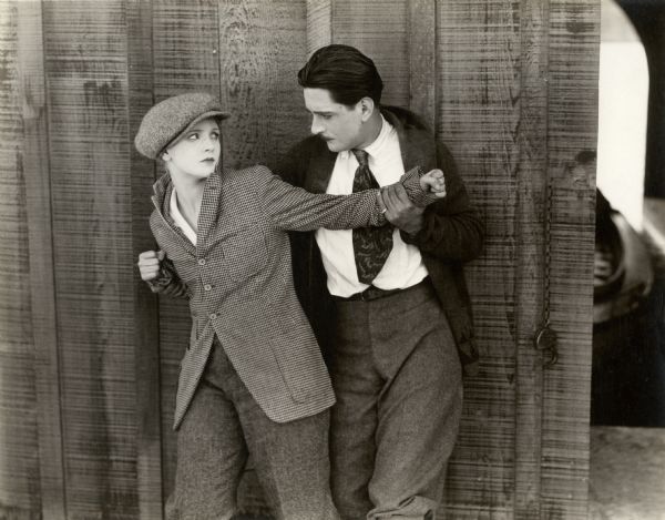 Dressed in her brother's clothes, Phyllis King (played by Mary Miles Minter) struggles with Grayson Blair (Alan Forrest) in a scene still for the silent drama "A Bit of Jade." Minter wears a checked jacket and cloth cap.
