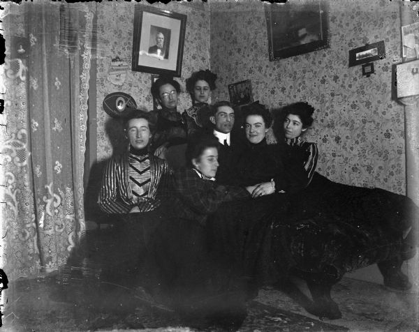 Man Surrounded by Six Women Indoor portrait of six women and a man posing sitting.