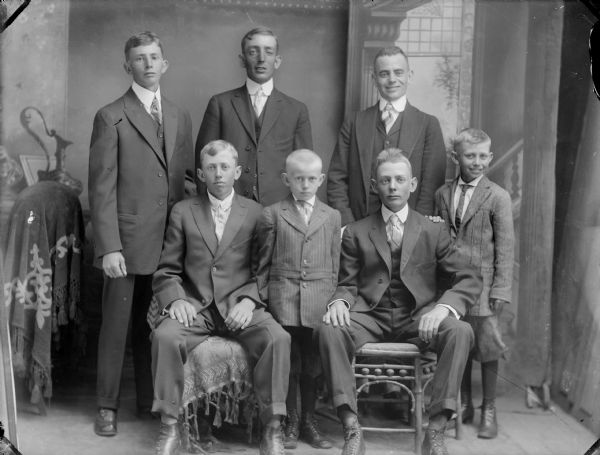 Studio Group Portrait of Elmer Ander Anderson and Others Studio portrait of three men posing standing behind two men posing sitting and two boys posing standing. The man in the center posing standing is identified as Elmer Anderson.