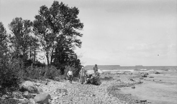 The photographer's children pose on the shore at Fish Creek Point. They are, from left, Ferdinand Leonard (Fedy), Alice, Margaret (Sissy), and Helen, who peers into the view finder of a camera.