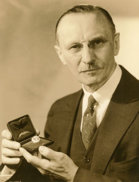 Ferdinand Hotz poses holding the 41.94 carat Emperor Maximilian Diamond, which he owned from 1919 to 1946. He is wearing pince nez glasses and a pearl tie stick pin. The diamond was part of an exhibit at the 1933 Chicago Worlds Fair (A Century of Progress.) Hotz was a jewelry designer and dealer in fine gemstones.