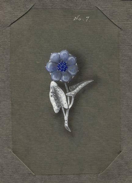 Hand-colored drawing on tissue, in a cardboard mount, of a design for a brooch in the form of a flower on a stem with two leaves. The flower is represented by large blue cabochons as petals and small, darker blue cabochons in the center. A filigree texture is indicated on the stem and leaves. "No. 7" is written at the top of the drawing.