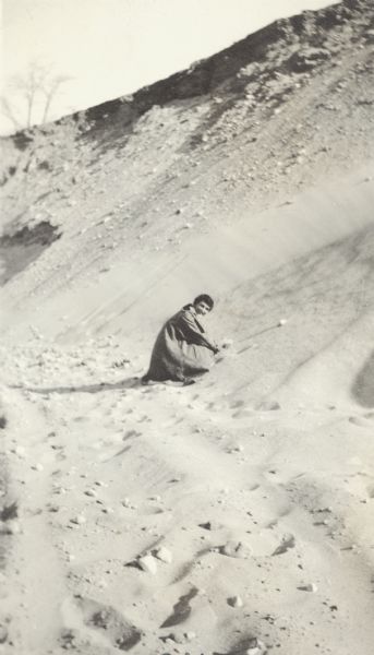 Woman Digging in a Sand Pit A woman, Grace, digs in the sand as she kneels in a sand pit near the intersection of Fish Hatchery Road and Park Street. A note on the back of the photograph reads, "Pieh's Hill, Keyes Hill."