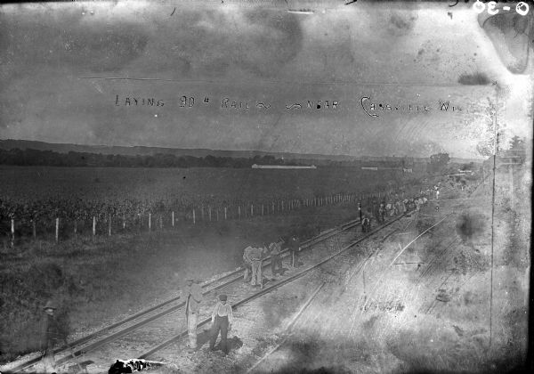 Elevated view of men working on the railroad near a farm field.