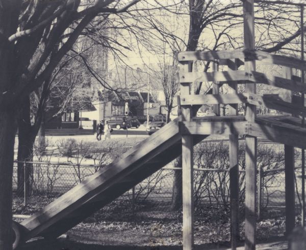 Playground Equipment at Neighborhood House Wooden playground structure on or near the grounds of Neighborhood House, with a McDonald's on Regent Street visible in the far background.