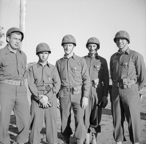 Wisconsin heroes in the Papuan campaign, a group of five award recipients at Camp Cable, near Brisbane, Australia. Left to right are Staff Sergeant Milan Miljatovich of Milwaukee, Private Steve Parks of Cameron, Captain Joseph Stehling of Beaver Dam, Sergeant Homer McGettigan of Darlington and Sergeant Hugo Arno of Menasha. Miljatovich and Parks received the Distinguished Service Cross and the others received the Silver Star Medal.