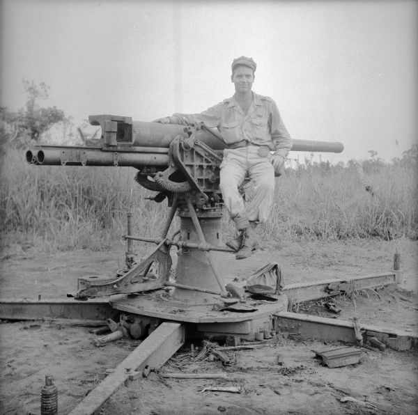 Robert Doyle seated on a Japanese cannon in Buna, New Guinea (present day Papua New Guinea). The Battle of Buna-Gona took place between November 16th, 1942 and January 2nd, 1943.