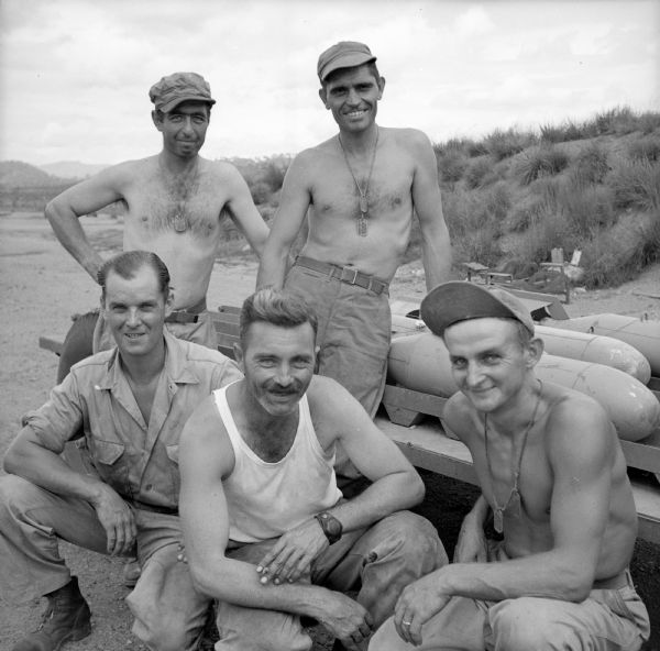 Michigan soldiers pose in front of a trailer loaded with bombs at a military base near Port Moresby, New Guinea (present day Papua New Guinea). Their names, left to right, are Sergeant Herman Rollin of Detroit, Sergeant Leonard Welch of Detroit, Sergeant Charles Sekula of Flint, Sergeant Edward Rushman of Wyandotte and Sergeant Joe Sankowski of Detroit.