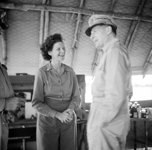 Four Star General Douglas MacArthur chats with Lieutenant Mildred McCausland of Wakefield, Rhode Island, during a tour on Goodenough Island, in the Solomon Sea, New Guinea (present day Papua New Guinea). They may be inside a hospital building.