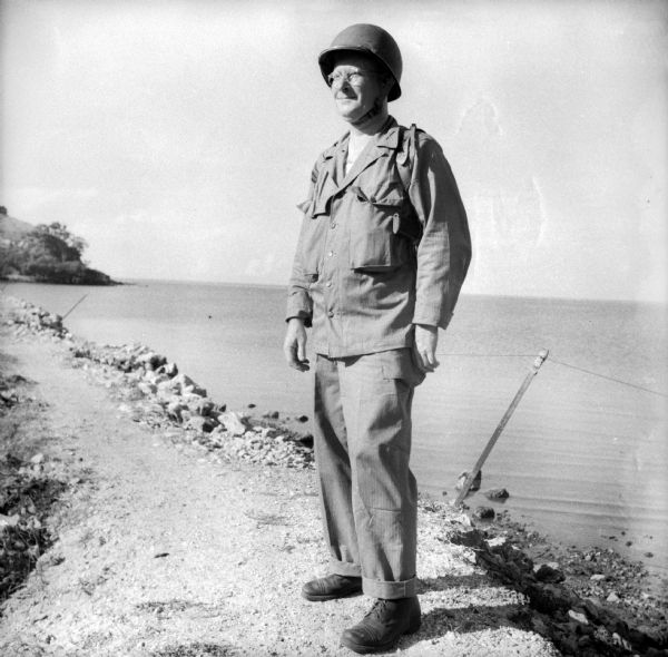 Robert Doyle's caption that accompanied this image reads, "Lieutenant Colonel Philip F. La Follette, three times Governor of Wisconsin, poses in combat uniform. He took part in the landings at Cape Gloucester, New Britain Island, in charge of a group of press correspondents." The ocean and shoreline are behind him.