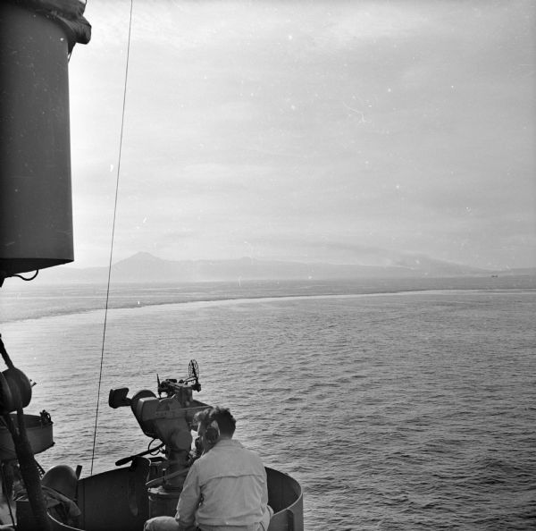 Elevated view from aboard ship looking down on a soldier in a turret operating a range finder. These warships were participating in the heavy bombardment of Cape Gloucester, New Guinea (present day Papua New Guinea), before the marines landed.