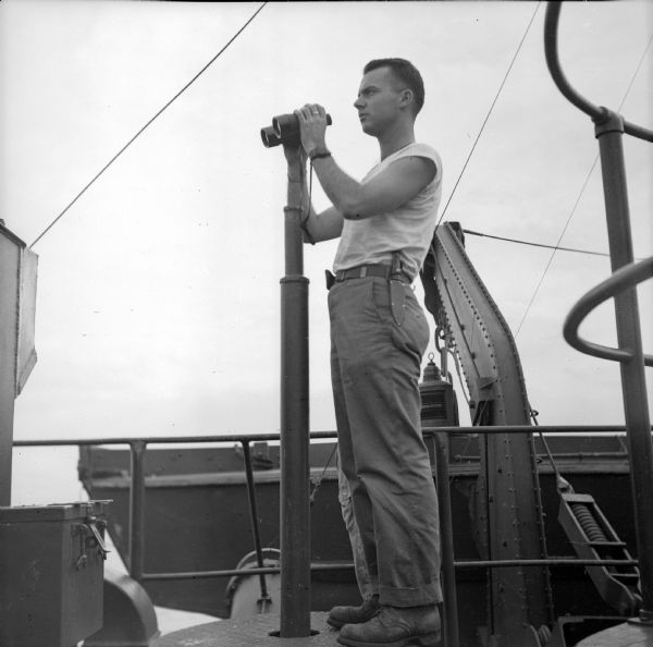 Robert Doyle on a LST (Landing Ship, Tank) after the landing at Saidor, New Guinea (present day Papua New Guinea). He has binoculars in his hands.
