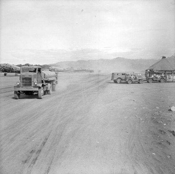 Military trucks, jeeps and planes at the Lae Airstrip, New Guinea (present day Papua New Guinea). Lae was a Japanese occupied airstrip until September 16, 1943, when it was liberated by the Allied Forces.