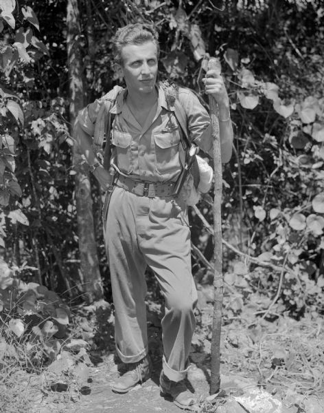 Major Arthur L. Post of Milwaukee, Wisconsin, was shot down on June 20th, 1943 and rescued on September 28th, 1943, after 101 days in the jungle. Here Post is wearing the seat cushion emergency kit exactly like the one he landed with in the jungle. It was attached to his parachute and contained the only food and medicine he had until he found an indigenous village. He also had a walking stick to help him walk with his injured knee. The military base where this image was taken was located near Port Moresby, New Guinea (present day Papua New Guinea). Robert Doyle was not allowed to publish Post's story at that time. It was finally published in January, 1947, by the <i>Milwaukee Journal</i>. Major Post intended to write his own story, but was killed in a test airplane on August 25th, 1944, before he had the chance.