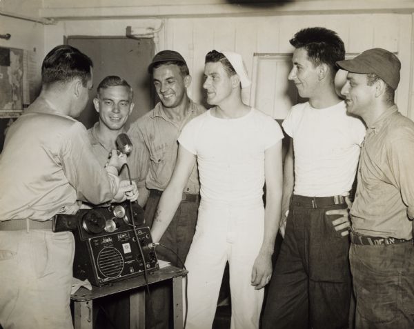 Robert Doyle, Journal war correspondent, took his wire recorder aboard the battleship <i>Wisconsin</i> while it was part of Admiral Halsey's 3rd fleet off the coast of Japan, to make one of his "Overseas With Bob Doyle" transcriptions, aired Sundays, 12:15 p.m., WTMJ. From left to right the lads interviewed by Doyle are: Frank Reiter, Seaman First Class; Ray Zuber, Seaman First Class; both from Milwaukee; Chester Sturgal, baker, of Ashland; Ralph Derdzinski, Quartermaster Second Class; and Joseph Dean, Jr., Seaman First Class, both of Milwaukee. The above information came from the caption that ran with the image in the <i>Milwaukee Journal</i>.