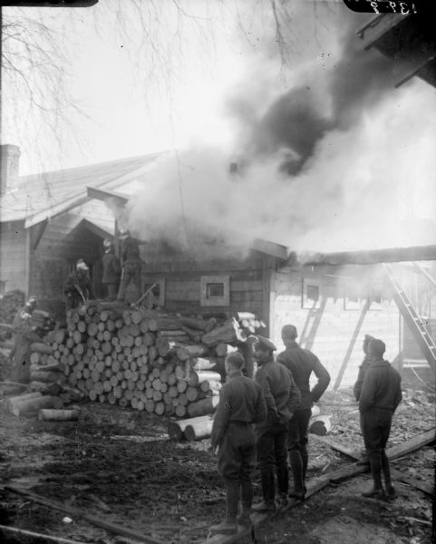 A group of soldiers look on as a group of Russian firefighters are attempting to extinguish a fire in a building possibly used by the Allied forces in Archangel [Archangelsk], Russia.