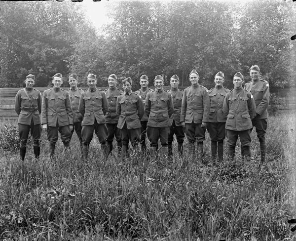 Group portrait of a lieutenant, (first on the left), and other soldiers in uniform from the 310th United States Army Engineers, standing, posing in a field.