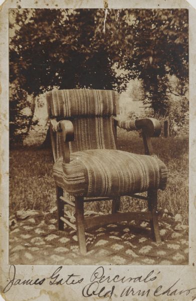 James Gates Percival's old armchair, upholstered with carpeting. The chair is displayed outdoors, sitting on a crocheted throw in the grass with trees in the background.