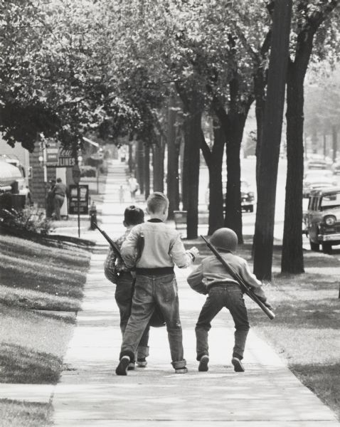 Residential street with three boys playing “soldier”.
