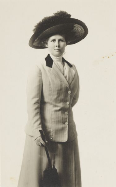 Studio portrait of “Mary”, standing with hat and parasol.